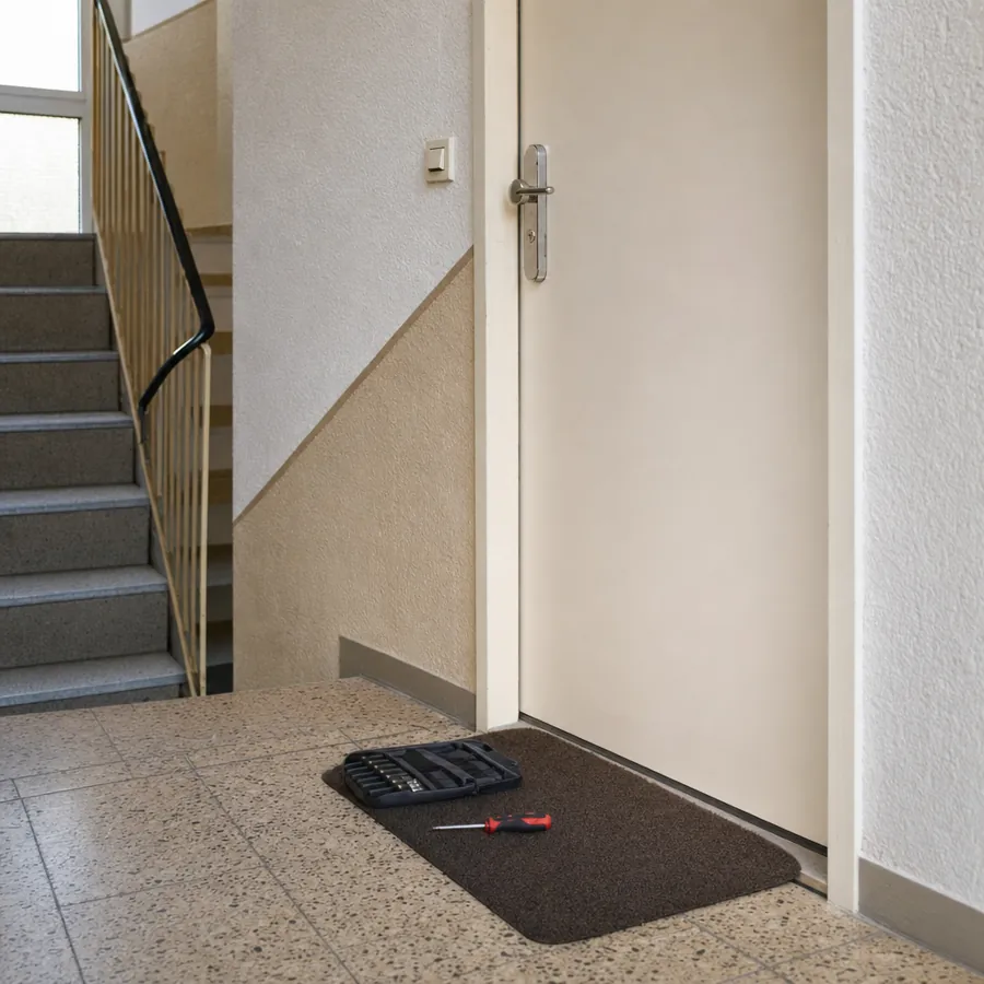 Wohnungstür im Treppenhaus mit Werkzeug für das Türschloss, symbolisches, KI-generiertes Bild